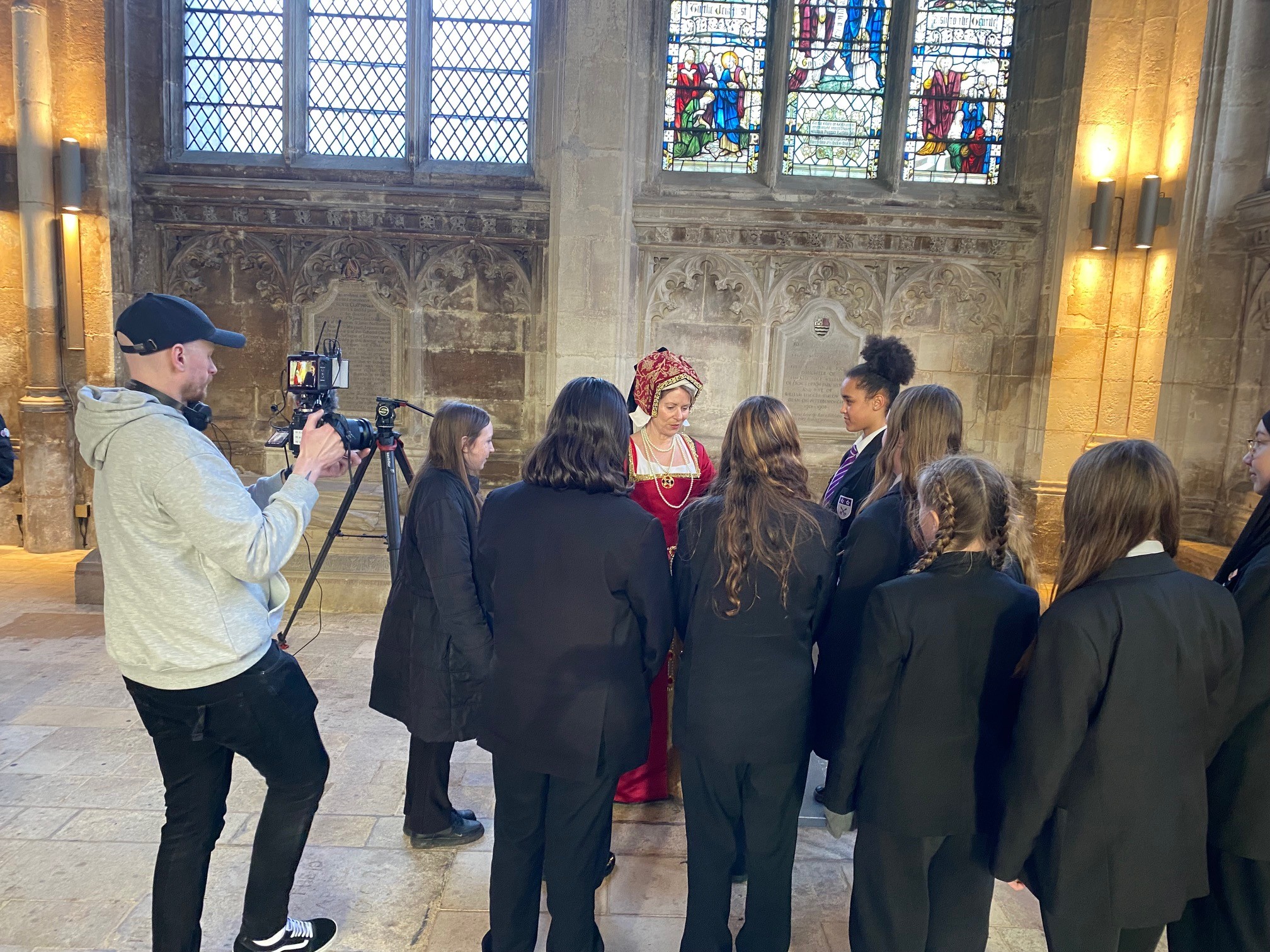 Students from Jack Hunt School stood with actress dressed as Katharine of Aragon inside Peterborough Cathedral.