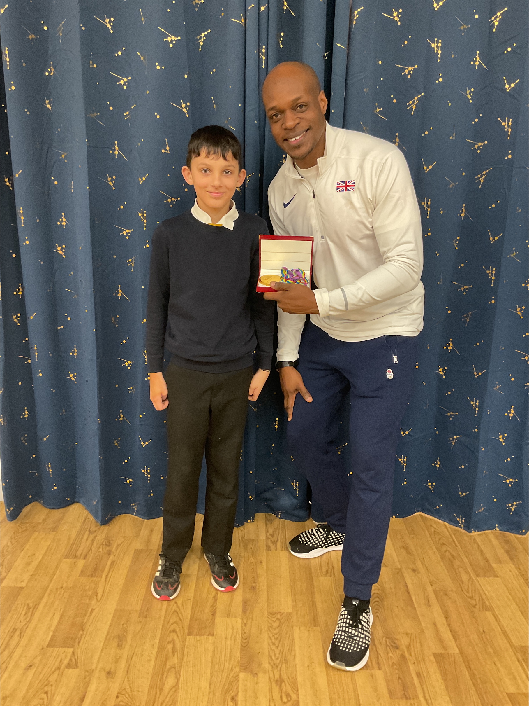 James Dasaolu showing his gold medal, stood with male pupil from Year 6 at Nova.